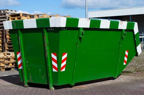 Operatives loading commercial waste into a skip with safety gear in Rotherhithe